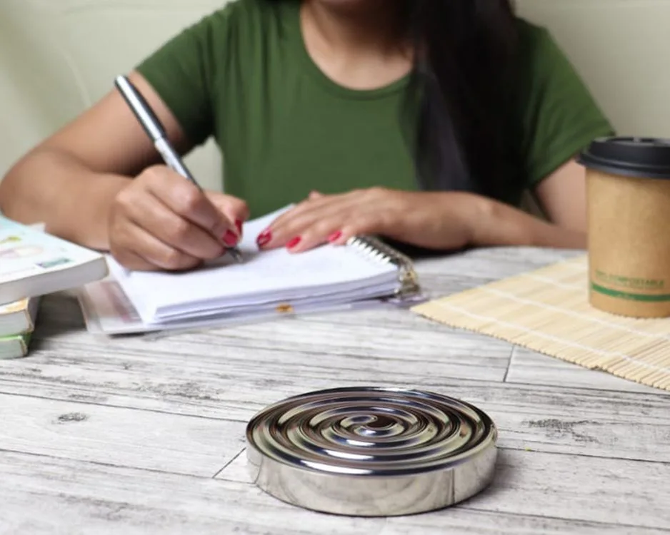 A person handwriting in a notebook at a desk with a cup of coffee, illustrating focused writing practice.