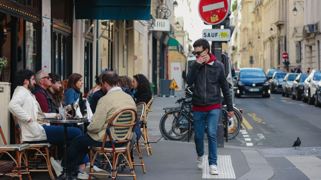People chatting at an outdoor café table on a Parisian street, evoking real-world French conversation practice.