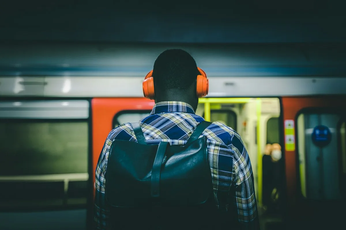 Commuter wearing headphones while waiting for a train, a typical setting for audio-only lessons